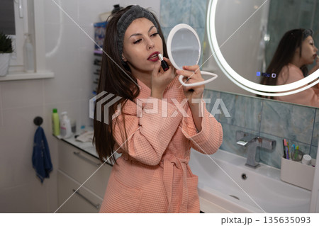Beautiful Woman Applying Lipstick in Bathroom Vanity Mirror Beautiful Woman Applying Lipstick in Bathroom Vanity Mirror 135635093
