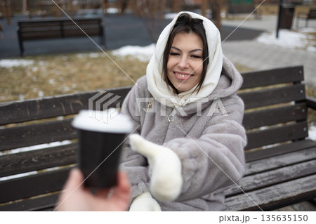 Woman in Winter Clothes Offered Coffee at Park in the Daytime Woman in Winter Clothes Offered Coffee at Park in the Daytime 135635150