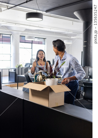 Colleagues in modern office unpacking boxes and discussing new workspace setup Colleagues in modern office unpacking boxes and discussing new workspace setup 135635247