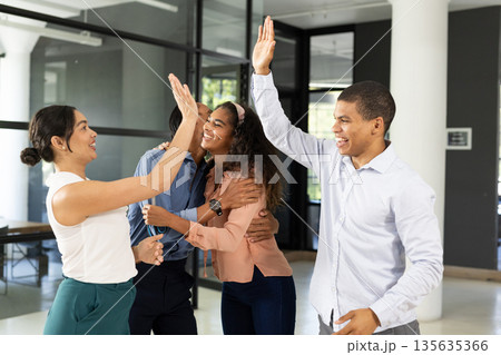 Diverse business team celebrating success with high fives in modern office 135635366
