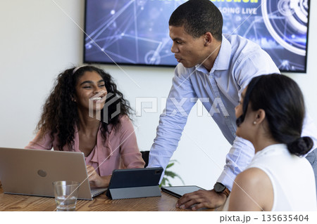 Discussing project with laptops, African American woman and colleagues in modern office Discussing project with laptops, African American woman and colleagues in modern office 135635404