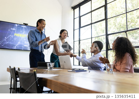 Diverse business team celebrating successful presentation in modern conference room 135635411