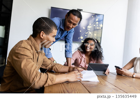 Diverse business team collaborating with tablet and documents in modern office 135635449