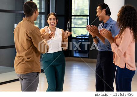 Business team celebrating colleague receiving award in modern office setting Business team celebrating colleague receiving award in modern office setting 135635450