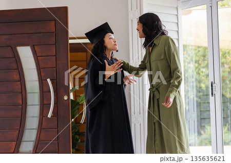 Graduation day, African American mother and daughter celebrating achievement at home 135635621
