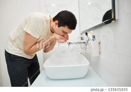 Man rinsing after brushing teeth over sink in modern bathroom Man rinsing after brushing teeth over sink in modern bathroom 135635835