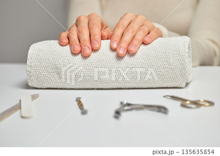 Woman hands with natural nails resting on a white towel, preparing for a manicure Woman hands with natural nails resting on a white towel, preparing for a manicure 135635854