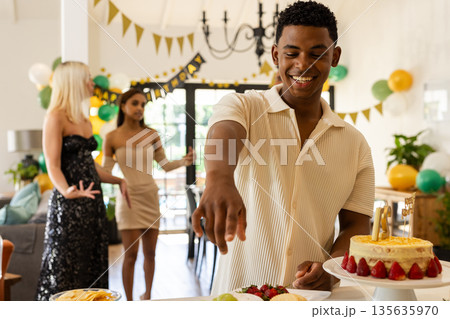 Serving cake at birthday party, man with friends celebrating in background Serving cake at birthday party, man with friends celebrating in background 135635970