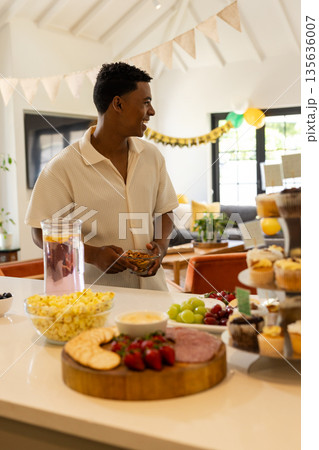 Man enjoying snacks and drinks at home during festive celebration Man enjoying snacks and drinks at home during festive celebration 135636007