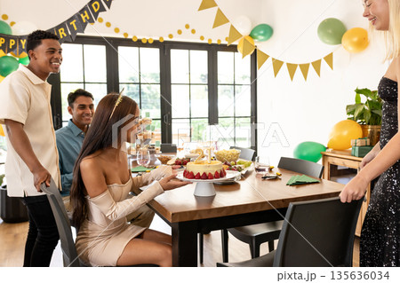 Friends gathering around birthday cake with decorations, celebrating and smiling happily Friends gathering around birthday cake with decorations, celebrating and smiling happily 135636034