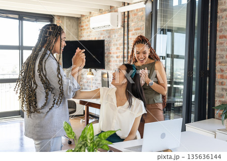 Colleagues celebrating success in modern office with high-fives and smiles 135636144