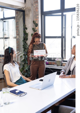 Presenting new project, woman holding tablet in modern office meeting 135636220