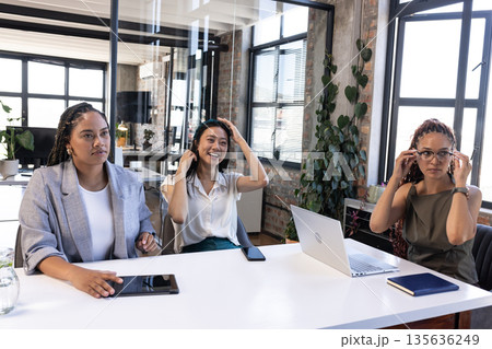 Businesswomen adjusting glasses and smiling during meeting in modern office Businesswomen adjusting glasses and smiling during meeting in modern office 135636249