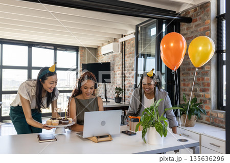 Celebrating birthday in office with cupcakes and balloons, colleagues smiling together 135636296