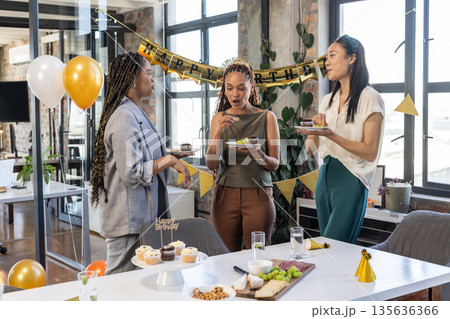 Celebrating in office, colleagues eating birthday cake and snacks with decorations 135636366