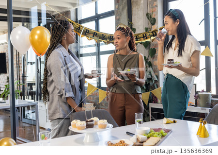 Colleagues celebrating birthday at office party with cake and decorations 135636369