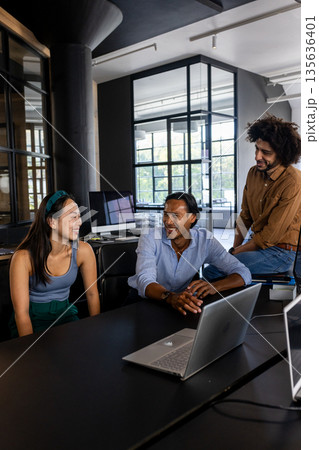 Asian woman and colleagues discussing project at office, smiling and engaged 135636401