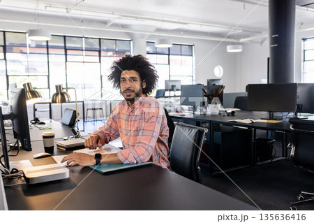 Confident businessman in modern office working on computer, focusing on tasks Confident businessman in modern office working on computer, focusing on tasks 135636416