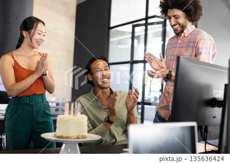 Celebrating birthday at office, diverse colleagues clapping around cake and smiling Celebrating birthday at office, diverse colleagues clapping around cake and smiling 135636424