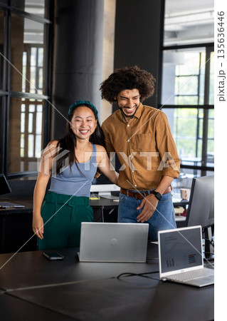 Colleagues in modern office smiling and collaborating on laptop project Colleagues in modern office smiling and collaborating on laptop project 135636446