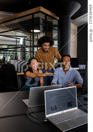 Asian woman and colleagues discussing project on computer in modern office 135636464