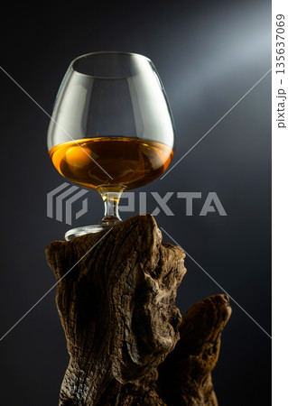 Glass of brandy on a old wooden snag. Glass of brandy on a old wooden snag. 135637069