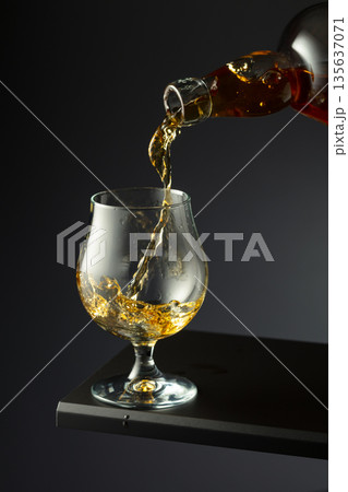 Cognac or brandy being poured into a glass. 135637071