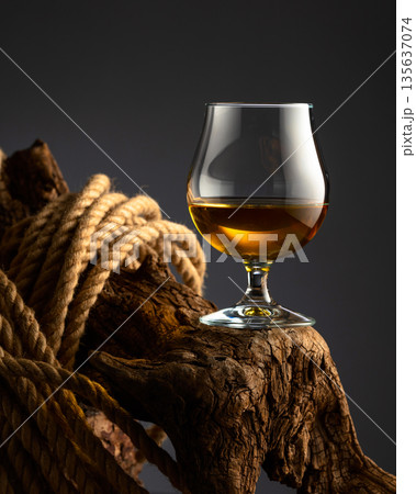 Brandy snifter and rope on a old wooden snag. Brandy snifter and rope on a old wooden snag. 135637074