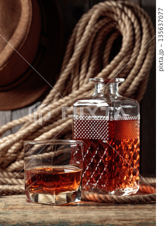 Glass and decanter with strong alcohol on a old wooden table. Glass and decanter with strong alcohol on a old wooden table. 135637077