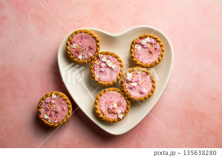 Valentine's day dessert. Pink mini tarts with heart shaped sprinkles in heart plate. Top view, copy space 135638280
