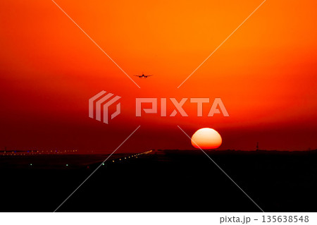 沈み行く夕日を背に着陸する飛行機 135638548