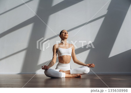 Lotus pose, meditation. Beautiful young woman with slim body type is indoors Lotus pose, meditation. Beautiful young woman with slim body type is indoors 135638998