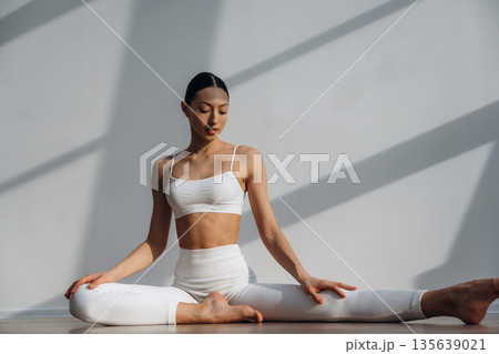 On the floor, doing yoga sport exercises. Beautiful young woman with slim body type is indoors 135639021