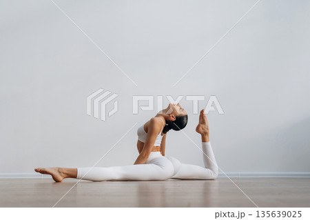 Sportive yoga exercise for flexibility. Beautiful young woman with slim body type is indoors Sportive yoga exercise for flexibility. Beautiful young woman with slim body type is indoors 135639025