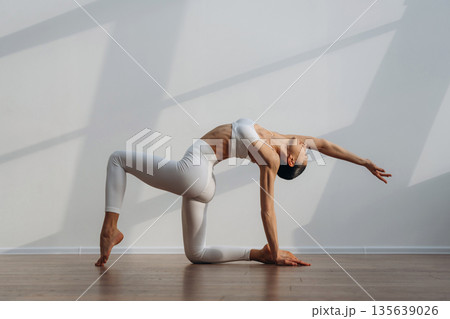 Sportive yoga exercise for flexibility. Beautiful young woman with slim body type is indoors 135639026