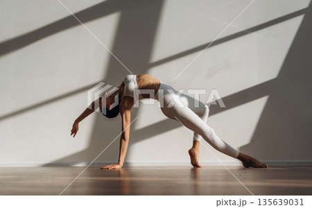 Physical activity, yoga exercises. Beautiful young woman with slim body type is indoors Physical activity, yoga exercises. Beautiful young woman with slim body type is indoors 135639031