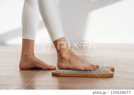 First step. Close up view of woman's legs that is standing on nails 135639077