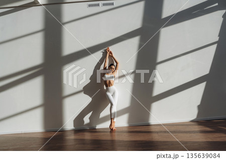 Leaning on the wall. Beautiful young woman with slim body type is indoors Leaning on the wall. Beautiful young woman with slim body type is indoors 135639084