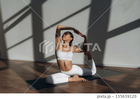 Health care, physical activity, sitting on the floor. Beautiful young woman with slim body type is indoors Health care, physical activity, sitting on the floor. Beautiful young woman with slim body type is indoors 135639120