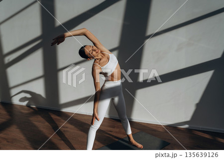 Warm up exercise. Beautiful young woman with slim body type is indoors 135639126