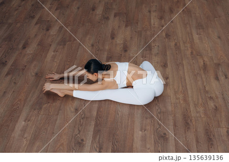 Enjoying doing yoga. Beautiful young woman with slim body type is indoors 135639136