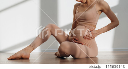Touching the abdomen. Pregnant woman is indoors Touching the abdomen. Pregnant woman is indoors 135639148