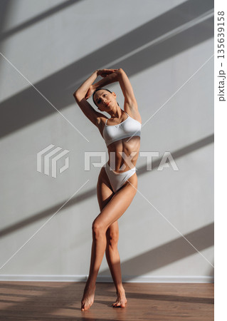 Demonstrating her body. Beautiful young woman is indoors Demonstrating her body. Beautiful young woman is indoors 135639158