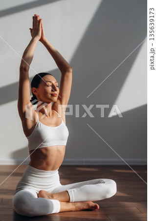 Calm mind, meditation in lotus pose. Beautiful young woman with slim body type is indoors Calm mind, meditation in lotus pose. Beautiful young woman with slim body type is indoors 135639173