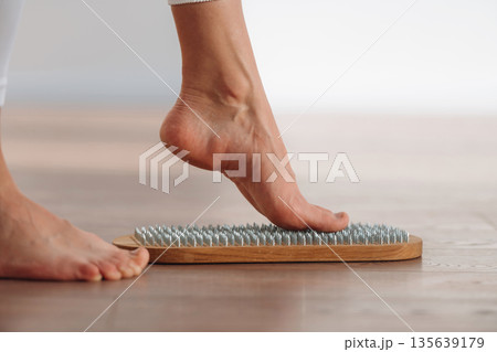 First step. Close up view of woman's legs that is standing on nails First step. Close up view of woman's legs that is standing on nails 135639179
