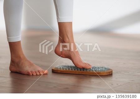 First step. Close up view of woman's legs that is standing on nails First step. Close up view of woman's legs that is standing on nails 135639180