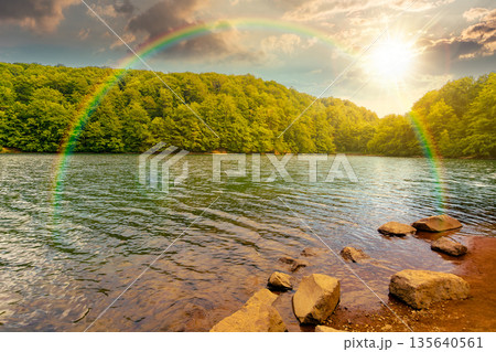 beautiful view of landscape with lake at sunset. body of water among beech forest in mountains in evening light. summer weather with clouds on the sky. timeless nostalgia book cover with rainbow 135640561
