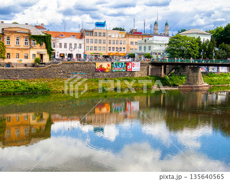 uzhhorod, ukraine - 29 jun, 2007: river uzh on a summer day. uzhhorod city travel background. panoramic view of a historic cityscape with bridge over water. urban landscape of old town in euroope uzhhorod, ukraine - 29 jun, 2007: river uzh on a summer day. uzhhorod city travel background. panoramic view of a historic cityscape with bridge over water. urban landscape of old town in euroope 135640565