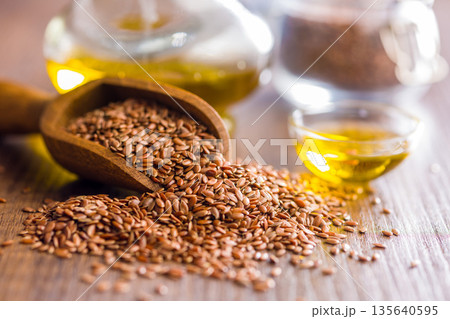 Brown linseed or flaxseed and oil. Healthy flax seed on wooden scoop on wooden table. Brown linseed or flaxseed and oil. Healthy flax seed on wooden scoop on wooden table. 135640595