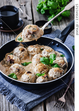 Chicken meatball on spoon over pan with sauce Chicken meatball on spoon over pan with sauce 135641525